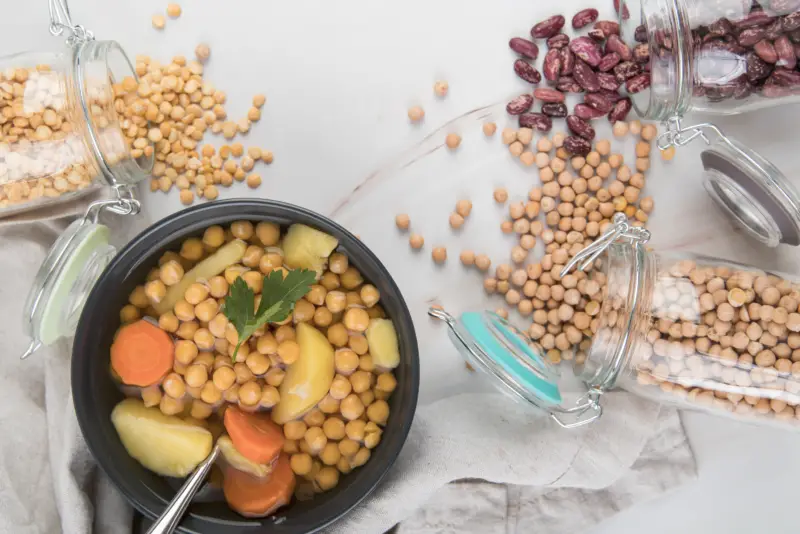 a bowl of food next to a jar of beans - Cook Pulses