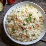 Lemon rice served with papad, chutney, and a glass of buttermilk.