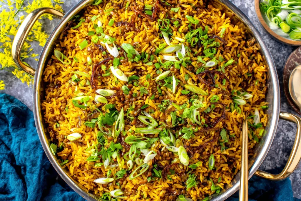 Mujadara (Lentils and Rice) garnished with scallions, cilantro, and caramelized onions in a large pot.