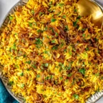 Mujadara (Lentils and Rice) topped with caramelized onions and fresh herbs in a serving bowl.