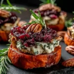 Sweet Potato Rounds with Brie Cranberry and Pecans topped with melted brie, dried cranberries, and toasted pecans on a dark serving board
