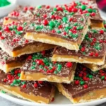 Christmas Crack stacked on a white plate with chocolate, toffee layers, and festive red and green sprinkles