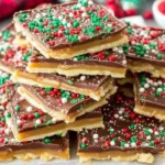 Christmas Crack topped with festive red, green, and white sprinkles stacked on a platter