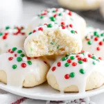 Soft Italian Christmas Cookies topped with white glaze and festive red and green sprinkles on a plate.