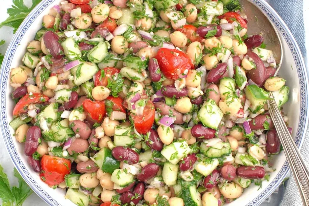 Mediterranean Bean Salad with chickpeas, kidney beans, cucumbers, tomatoes, red onion, and fresh herbs in a bowl