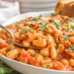 Close-up of Baked Cannelini Beans with creamy tomato sauce and melted cheese in a serving dish
