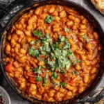 Loubia Recipe served in a cast iron skillet with white beans in rich tomato sauce