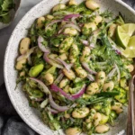 Marinated Cilantro Lime Bean Salad with creamy herby dressing, white beans, red onion, and fresh cilantro in a ceramic bowl