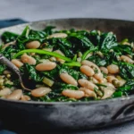 Sautéed Garlic Spinach and White Beans cooked in a skillet with olive oil and fresh greens