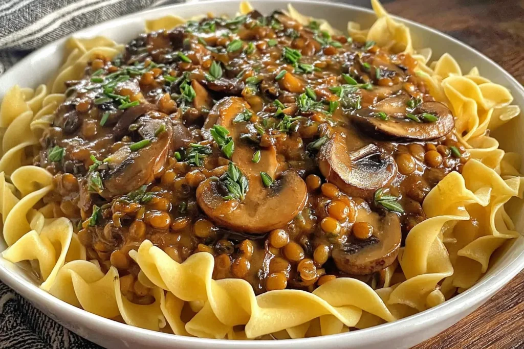 Vegan Lentil Mushroom Stroganoff with mushrooms and lentils on pasta, garnished with herbs