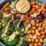 Roasted Veggie Chickpea Bowls with quinoa, roasted broccoli, sweet potatoes, chickpeas, and creamy tahini dressing in a black bowl.