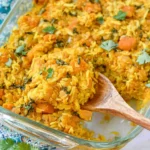 Red Lentil Casserole in a glass baking dish with basmati rice, sweet potato, herbs, and a wooden spoon scooping a serving.
