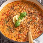 Creamy Marry Me Lentils simmering in a skillet with sun-dried tomatoes, basil, and lemon slices.