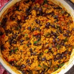 One-pot Black Beans and Rice in a red Dutch oven with tomatoes, peppers, and warm spices.