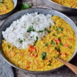 Red Lentil Dahl served with fluffy basmati rice, topped with fresh cilantro in a cozy bowl.