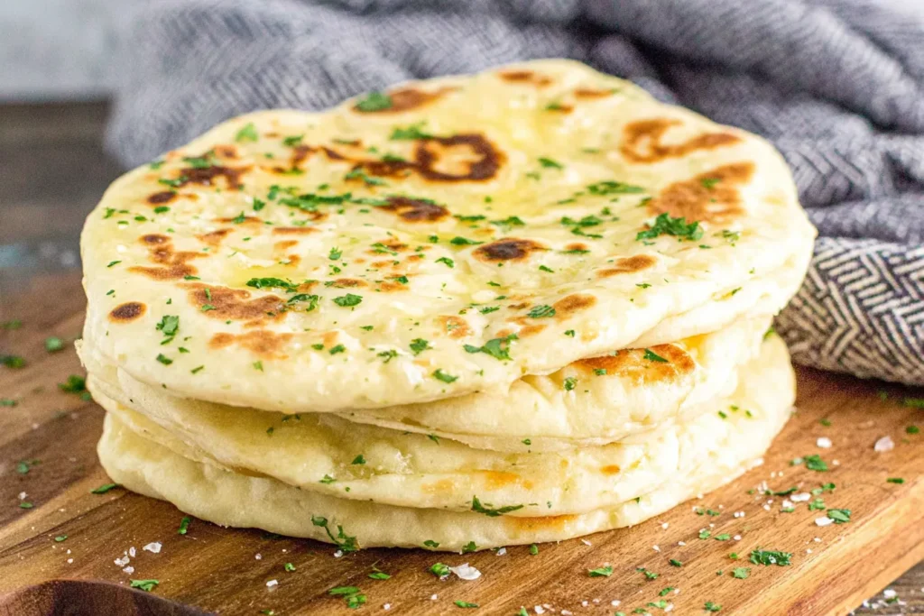 Easy Flatbread Recipe stacked on wooden board with flaky salt and fresh herbs