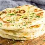 Easy Flatbread Recipe stacked on wooden board with flaky salt and fresh herbs
