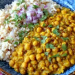 Easy Split Pea Curry served with fluffy white rice, topped with chopped red onion and fresh cilantro in a blue bowl.