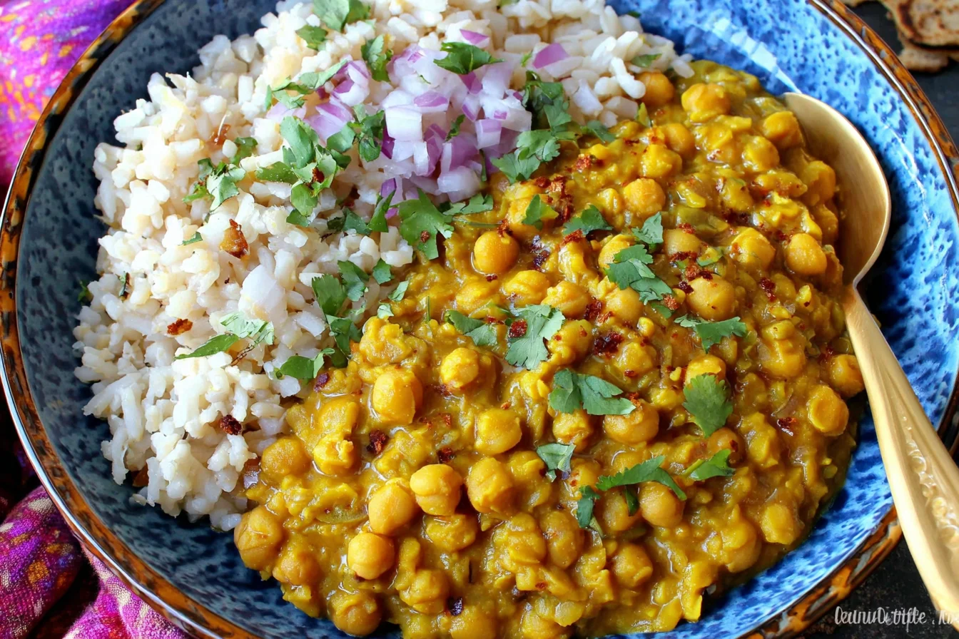 Easy Split Pea Curry served with fluffy white rice, topped with chopped red onion and fresh cilantro in a blue bowl.
