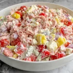 Close-up of Italian Grinder Chicken Salad Recipe with shredded chicken, provolone, feta, grape tomatoes, and red onion in creamy dressing
