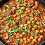 Lebanese Chickpea Stew in a black bowl, rich tomato broth with tender chickpeas and fresh parsley on top.
