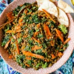 Moroccan Lentil Carrot Salad in a ceramic bowl with kale, sliced carrots, and pita wedges, served with lemon on the side.