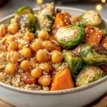 Winter Veggie Chickpea Bowl with roasted sweet potatoes, Brussels sprouts, chickpeas, and fluffy quinoa in a white bowl.