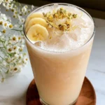 Refreshing Banana Chamomile Tea Smoothie garnished with dried chamomile flowers and banana slices in a tall glass