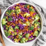 Broccoli Salad with Honey Dijon Dressing mixed with bacon, cabbage, and carrots in a bowl