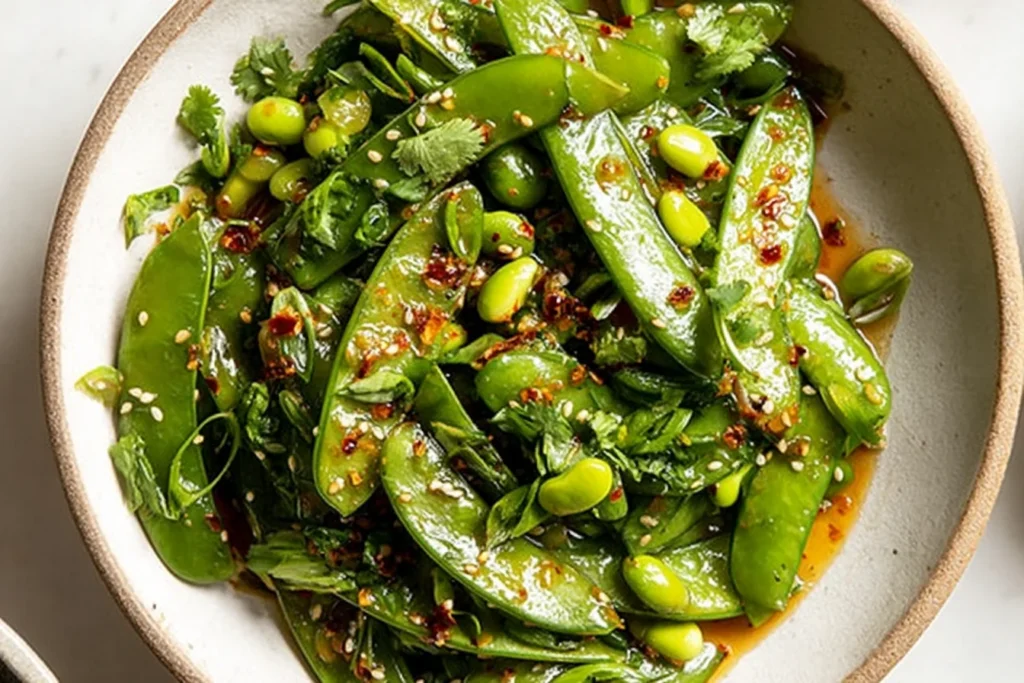 Chili Crisp Snap Pea Salad with edamame, sesame seeds, and fresh cilantro in a glossy chili oil dressing