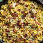 Creamy Chicken and Corn Pasta with Bacon in a skillet with bow-tie pasta, grilled chicken, corn, and crispy bacon