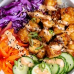 Bang Bang Tofu bowl with crispy tofu, rice, purple cabbage, carrots, and cucumber topped with creamy spicy sauce