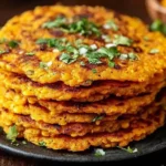 Savory Red Lentil Pancakes stacked with crispy edges and fresh herbs on top, served warm on a plate
