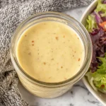 Jar of Everyday Creamy Vinaigrette next to fresh mixed greens salad