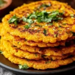 Savory Red Lentil Pancakes stacked golden and crispy with fresh herbs on top, showing texture and homemade detail