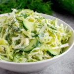 Green Cabbage Cucumber Salad with fresh dill and sliced cucumbers in a white bowl