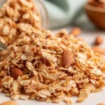 Healthy Homemade Granola Recipe with crunchy oat clusters and almonds spilling from a glass jar