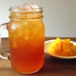 Homemade Mango Iced Tea in a mason jar with ice and fresh mango slices