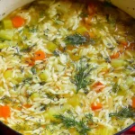 Orzo Leek and Dill Soup simmering in a pot with tender orzo, fresh dill, carrots, and leeks in a light broth