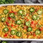 Baked Jalapeño Buffalo Chicken Casserole in a dish topped with jalapeños, red peppers, and herbs