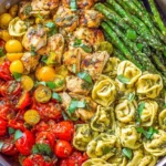 Pesto Chicken Tortellini and Veggies with grilled chicken, asparagus, cherry tomatoes, and basil pesto in a skillet