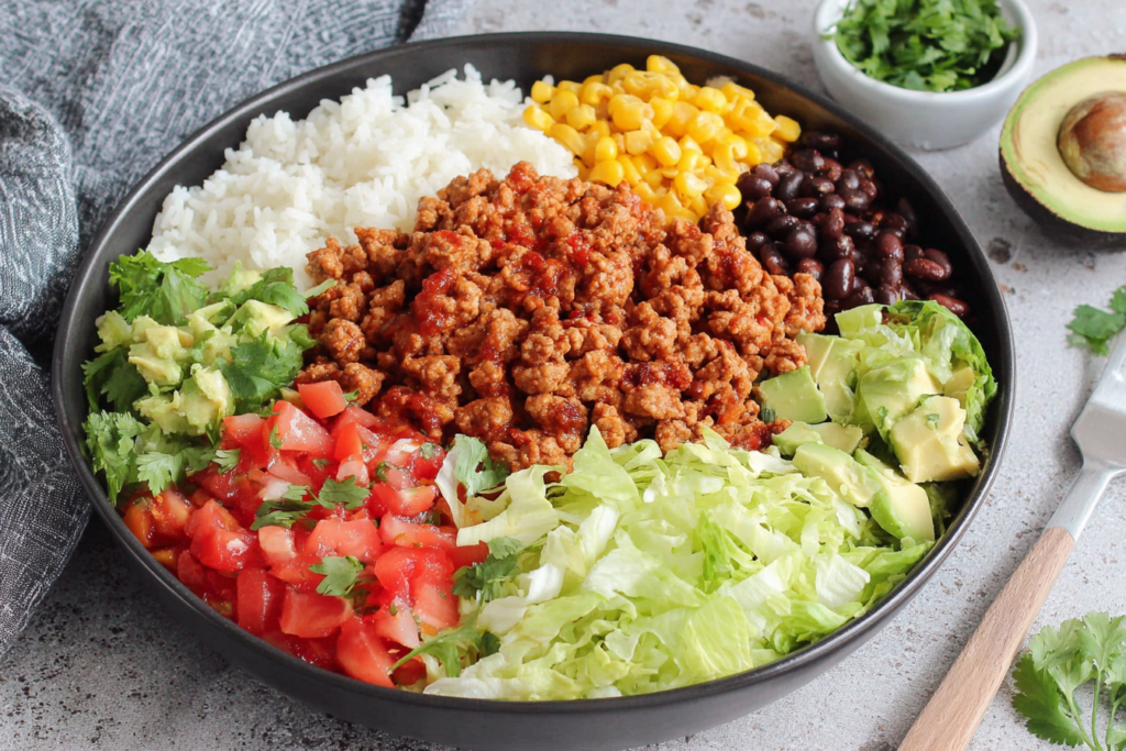 Taco Lunch Bowls with ground turkey, white rice, corn, black beans, and avocado in a meal prep bowl