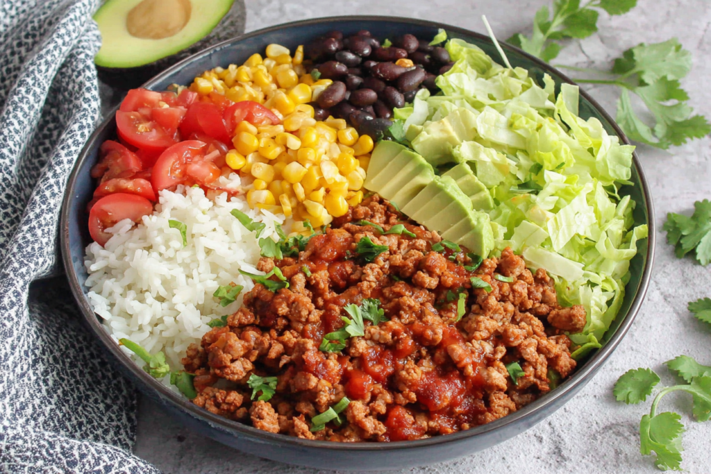 Colorful Taco Lunch Bowls with turkey meat, rice, corn, beans, avocado, and lettuce