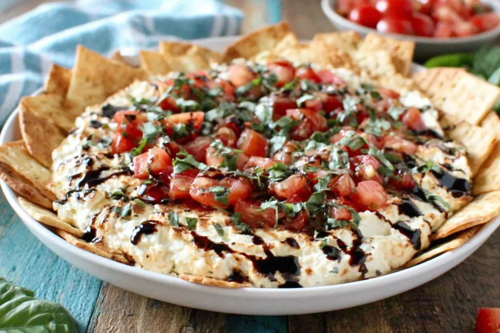 Bruschetta Dip served with crackers, topped with tomatoes, basil, and balsamic glaze