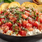 Bruschetta Dip Recipe topped with basil and parmesan served with crostini slices