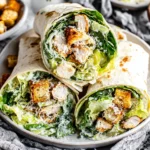 Chicken Caesar Wrap served on plate with Parmesan cheese and fresh greens