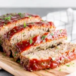 Classic Meatloaf slices with ketchup glaze on a rustic cutting board