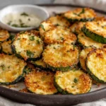 Crispy Zucchini Chips Recipe on a plate with garlic parmesan seasoning and herbs