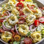 Fresh Grinder Tortellini Salad served in a bowl with tomatoes and red onion