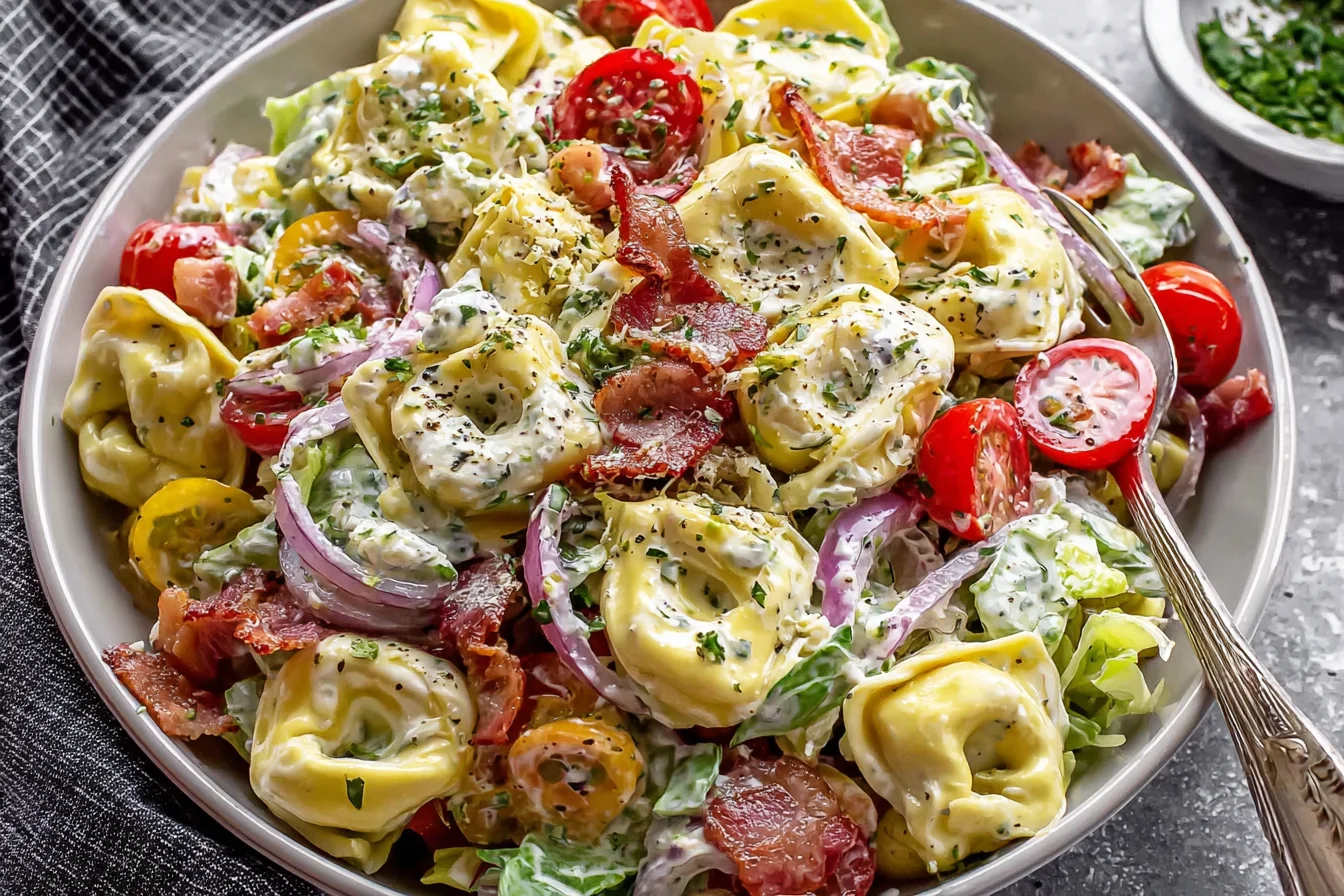Fresh Grinder Tortellini Salad served in a bowl with tomatoes and red onion